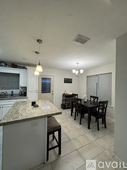 A kitchen with granite countertops and a dining table with chairs.