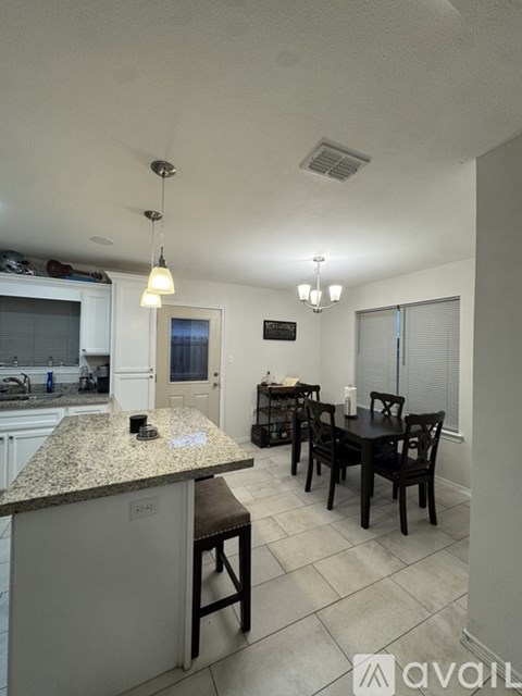 A kitchen with granite countertops and a dining table with chairs.