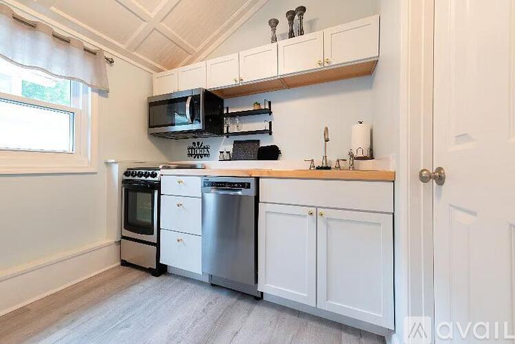A kitchen with white cabinets and a stainless steel dishwasher and oven.