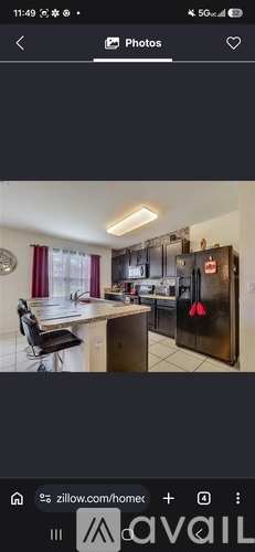A modern kitchen with a black refrigerator and a dining area with a table and chairs.