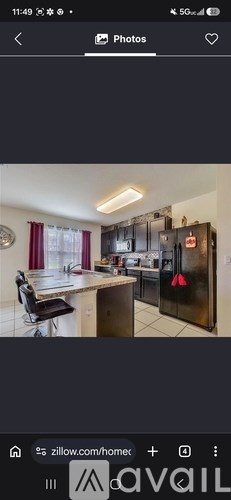 A modern kitchen with a black refrigerator and a dining area with a table and chairs.