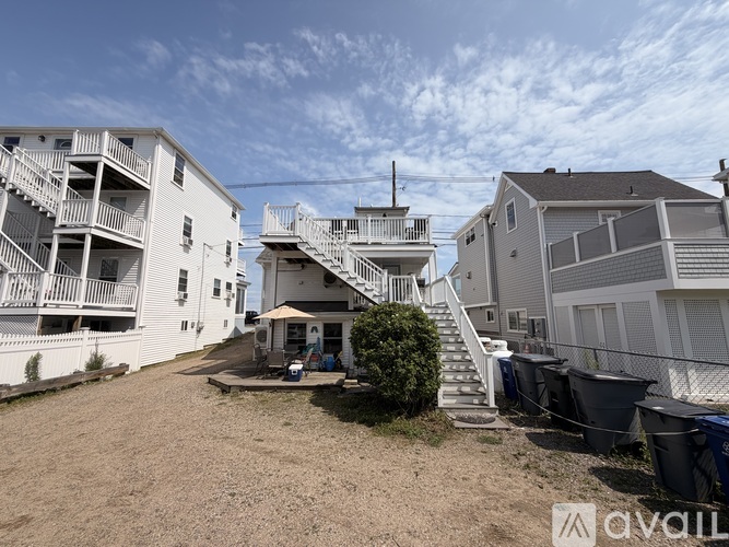 A sunny day at a beachfront property with a white building and a patio area.