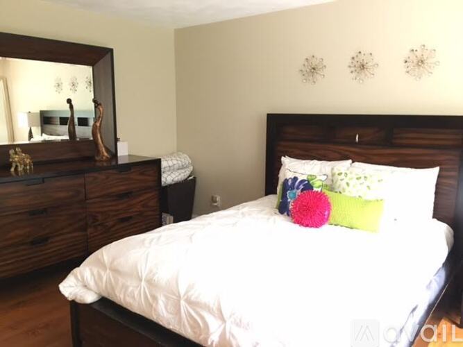 A bedroom with a large bed and a dresser with a mirror.
