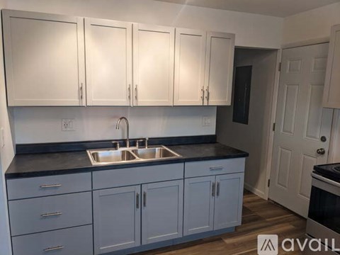 A kitchen with white cabinets and a black countertop.