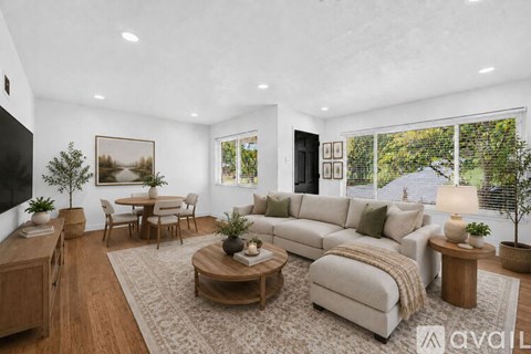 A living room with a large couch, a coffee table, and a painting on the wall.