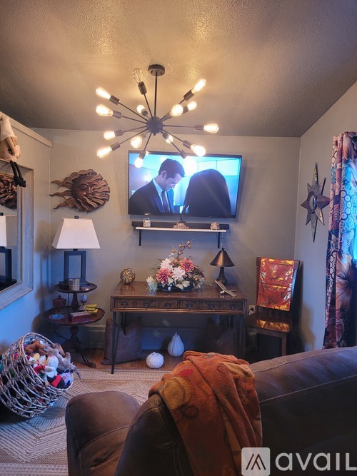 A living room with a couch, a table with a lamp, and a television playing a show.