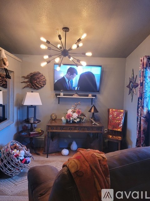 A living room with a couch, a table with a lamp, and a television playing a show.