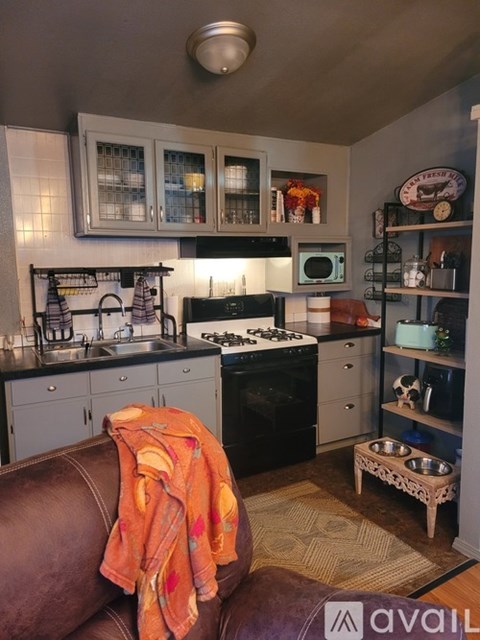 A kitchen with a black stove top oven and a black microwave above the stove.
