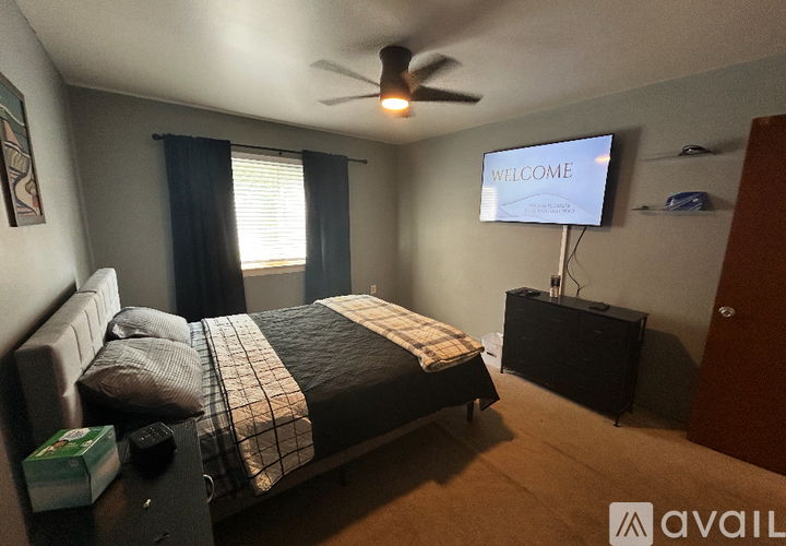 A bedroom with a bed, a ceiling fan, and a TV displaying "Welcome".
