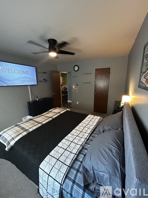A bedroom with a bed, a ceiling fan, and a TV screen displaying the word "WELCOME".