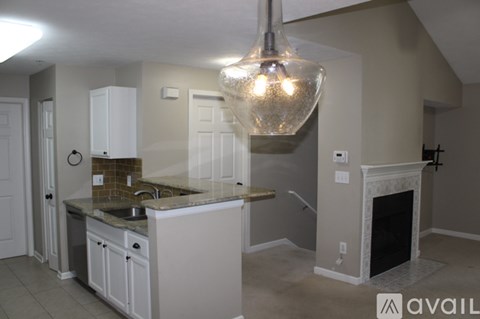 A kitchen with a white counter top and a chandelier hanging from the ceiling.