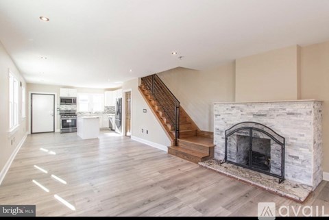 A spacious living room with a fireplace and a staircase leading to the upper floor.