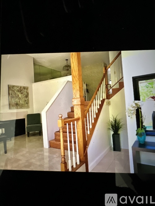 A staircase with a wooden banister and a green plant on the side table.