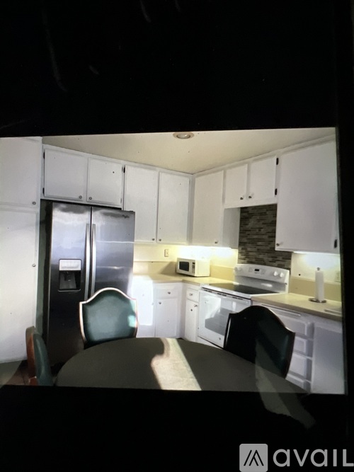 A kitchen with white cabinets and a black fridge.