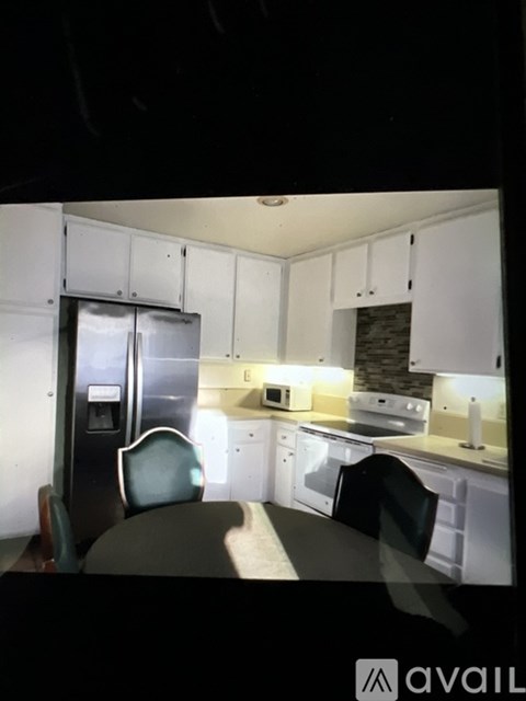 A kitchen with white cabinets and a black fridge.