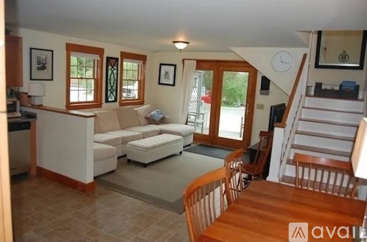 A living room with a couch, chairs, and a staircase.