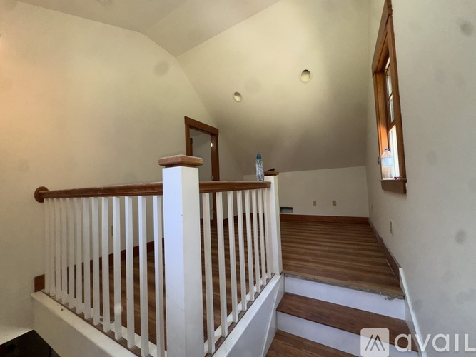 A staircase with a wooden handrail and white balusters leads to a second floor.