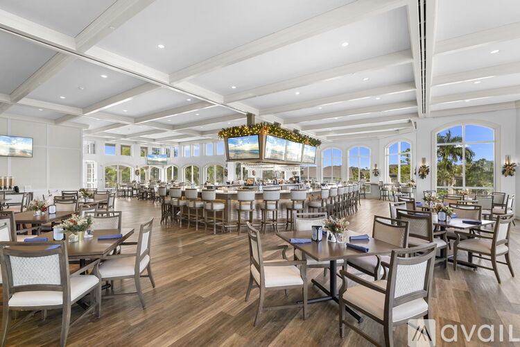 A large, well-lit dining room with wooden floors and multiple tables set for dining.