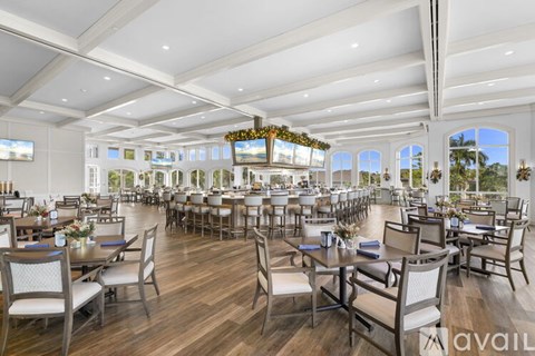 A large, well-lit dining room with wooden floors and multiple tables set for dining.