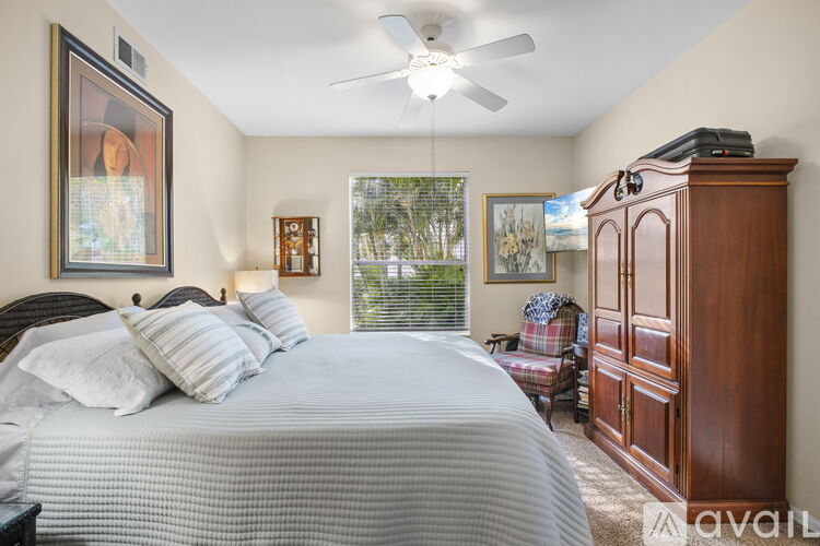 A bedroom with a large bed, a ceiling fan, and a wooden cabinet.