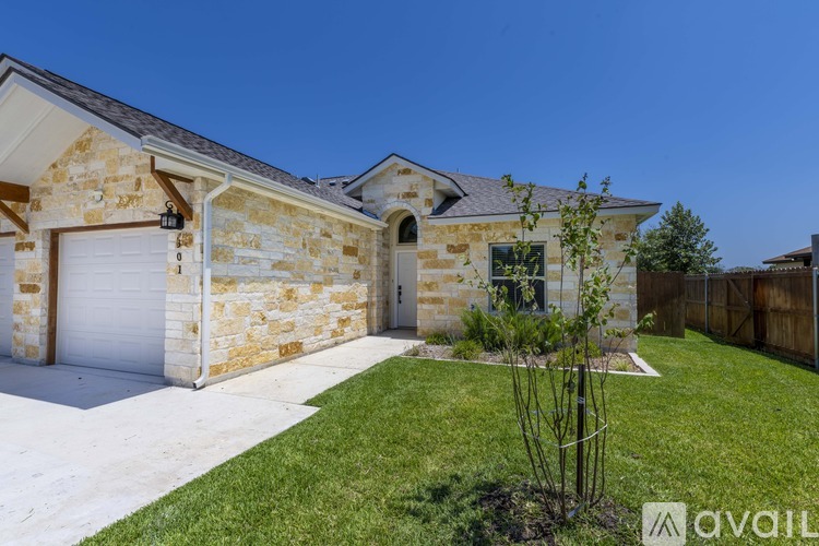 A stone house with a white garage door and a small tree in front.
