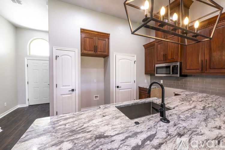 A kitchen with a marble countertop and a modern chandelier.