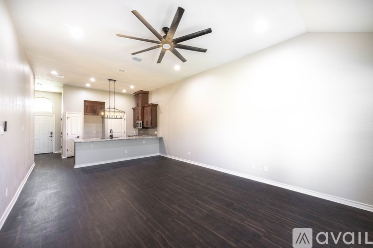 A spacious room with a ceiling fan and wooden flooring.