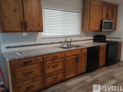 A kitchen with wooden cabinets and black appliances.