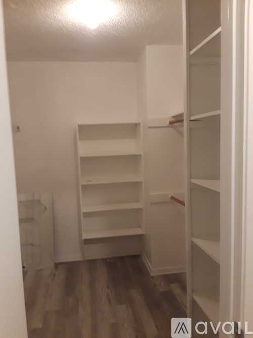 A white closet with shelves and a wooden floor.