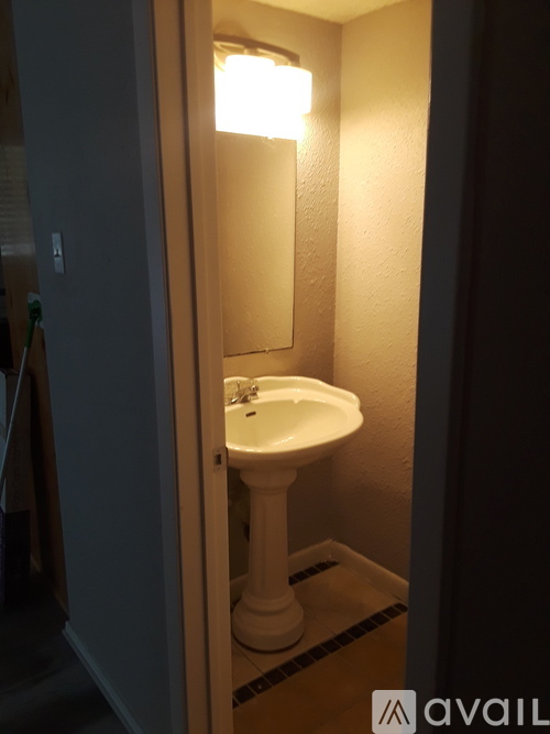A white pedestal sink in a small bathroom.