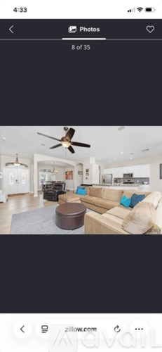 A living room with a beige sofa and a brown ottoman.