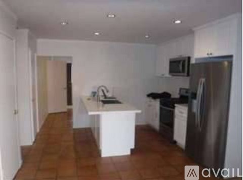 A kitchen with a refrigerator, sink, and cabinets.