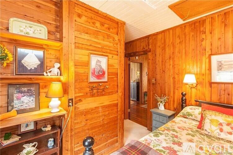 A bedroom with wooden walls and a bed with a floral comforter.
