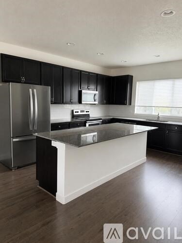 A kitchen with black cabinets and a stainless steel refrigerator.