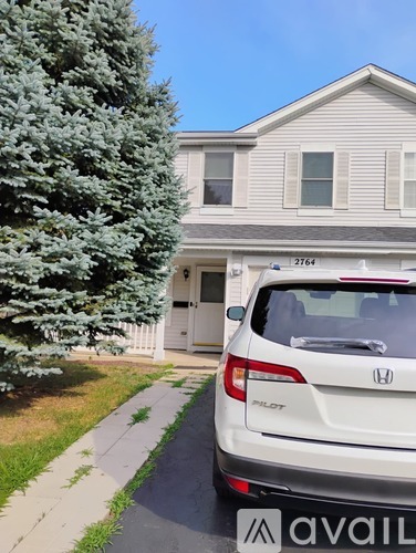 A white Honda Pilot is parked in front of a house with the number 2764 on it.