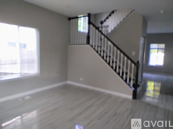 A spacious room with wooden floors and a staircase.