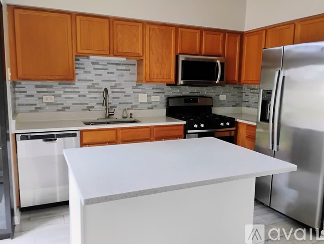 A kitchen with wooden cabinets and a white island.