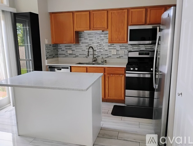 A kitchen with wooden cabinets and a white island.