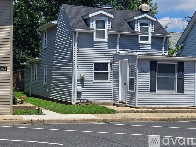 A two-story house with a grey siding and a white door.