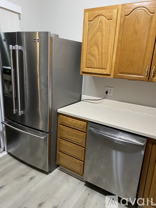 A kitchen with a stainless steel refrigerator and wooden cabinets.