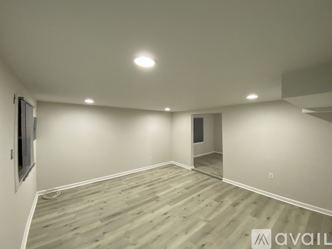 A spacious room with wooden flooring and recessed lighting.