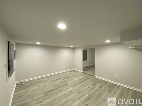 A spacious room with wooden flooring and recessed lighting.