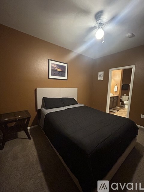 A bedroom with a bed, nightstand, and a ceiling fan.