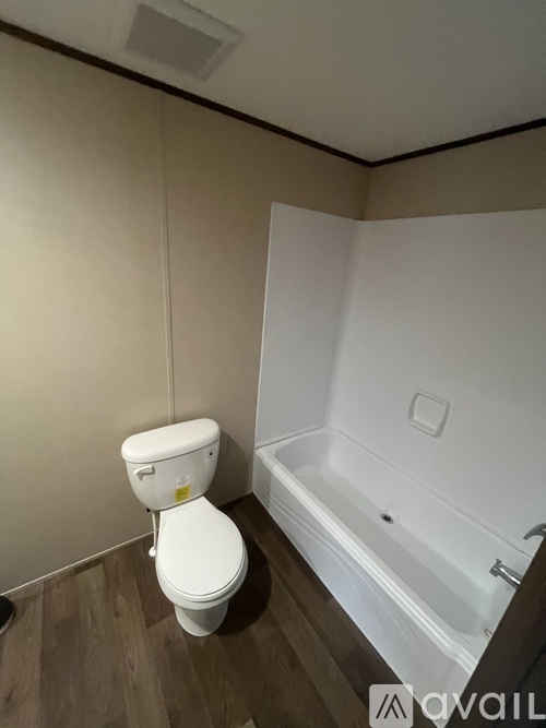 A white toilet is in a small bathroom with a white bathtub.