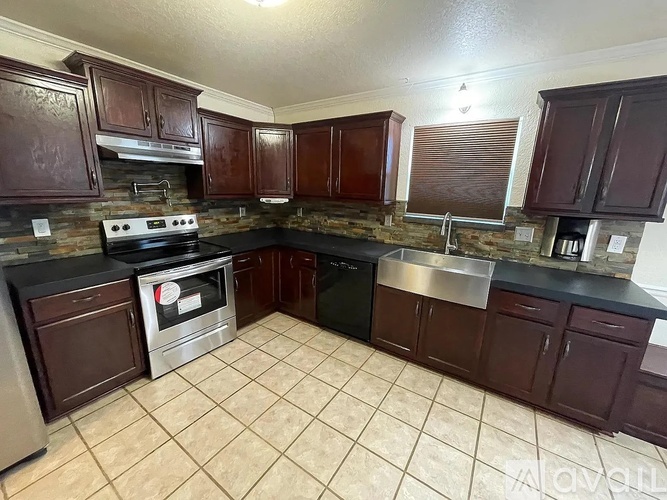 A kitchen with dark wood cabinets and a black stove top oven.