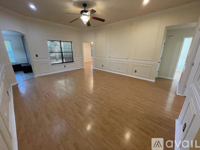 A spacious room with wooden flooring and a ceiling fan.