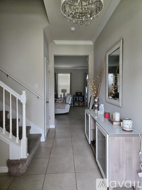 A hallway with a staircase and a mirror on the wall.