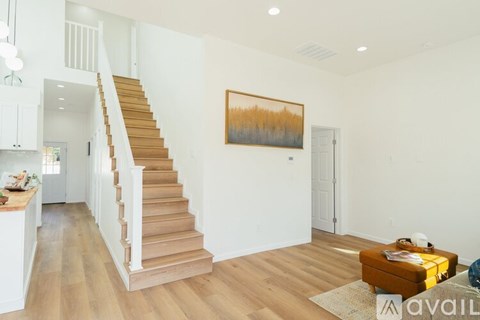 A living room with a staircase and a painting on the wall.