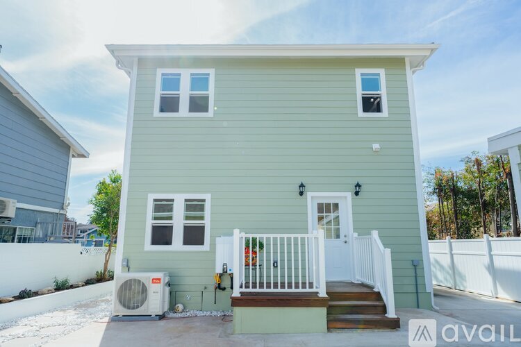 A house with a green exterior and a white porch is for sale.
