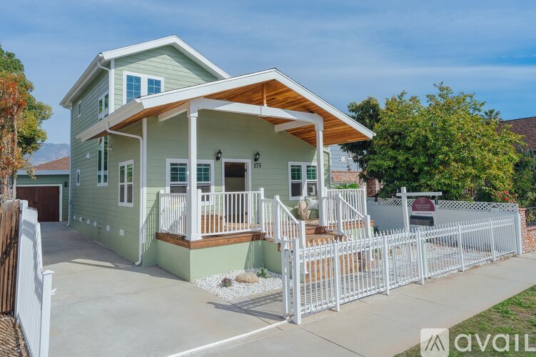 A house with a green exterior and a white picket fence.